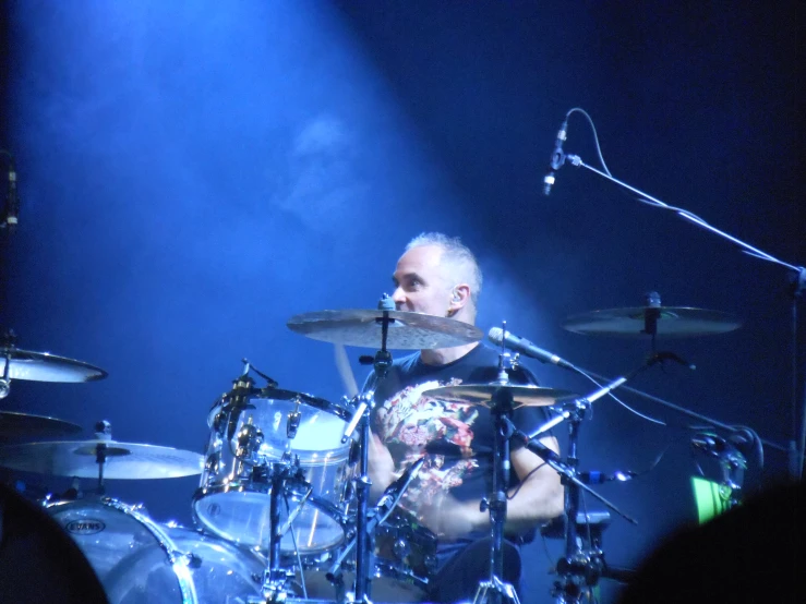 a man with tattoos playing drums while holding a microphone