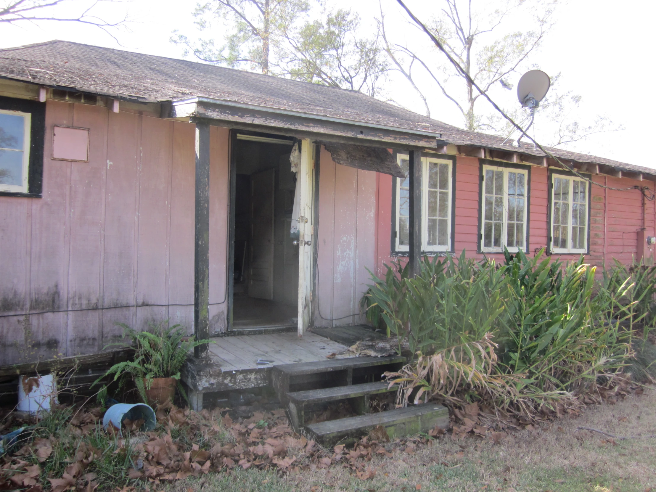 a pink old building with a porch and steps