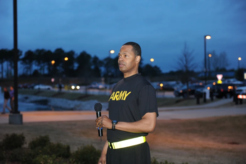a man standing in a parking lot holding a microphone