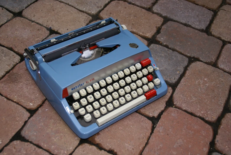 an old - fashioned typewriter sits atop a brick walkway