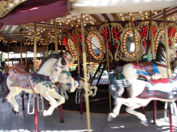 two white horses are riding on a merry go round