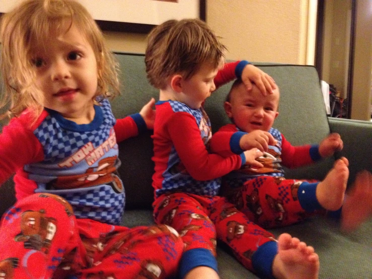 three babies are sitting on a couch together