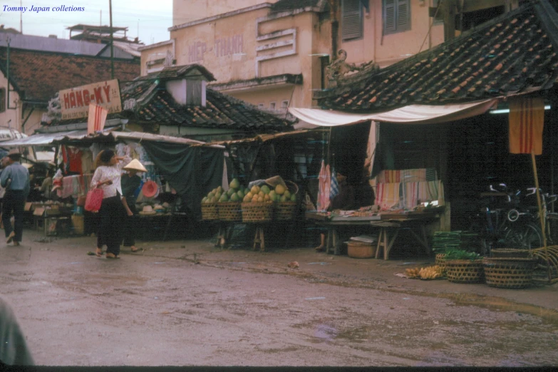 people are shopping at an outdoor market near tall buildings