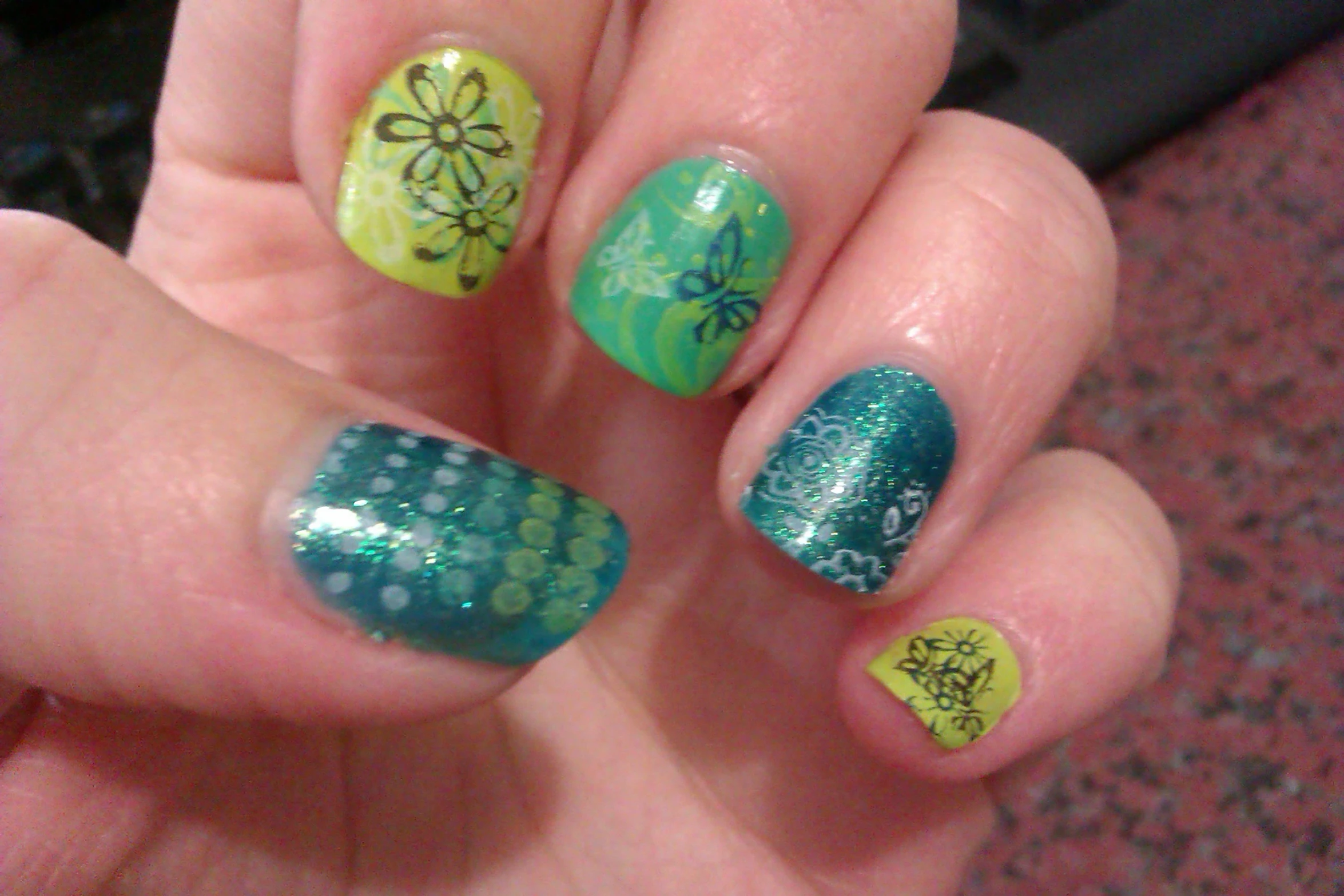 a hand with green, yellow and yellow nail art