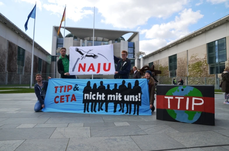 several people holding signs with flags in the background