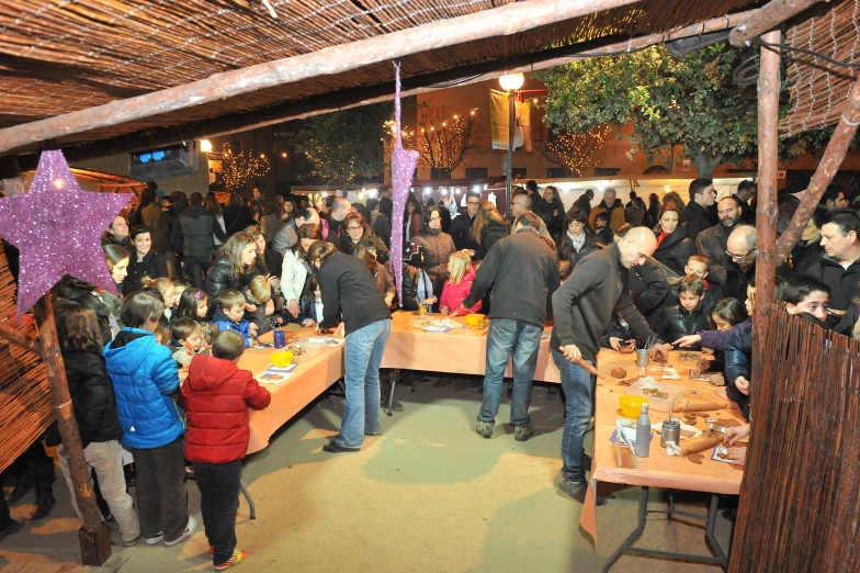 a number of people standing near one another near a table with cake