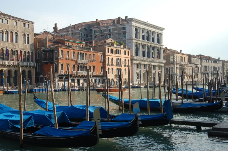 several blue gondola sit in the water near other buildings