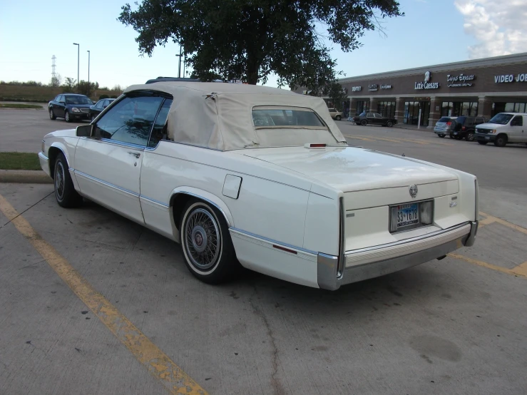 the back of a white convertible car parked in a parking lot