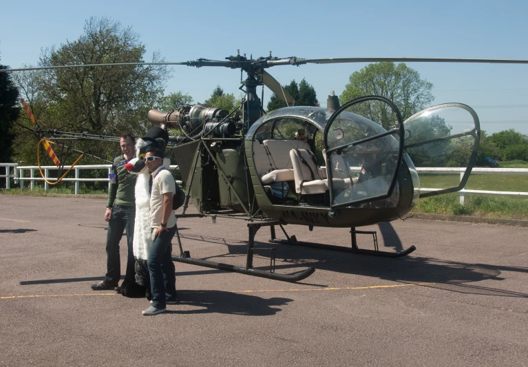 a man and woman standing in front of a helicopter