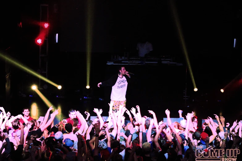 a crowd of people at a concert raising their hands up