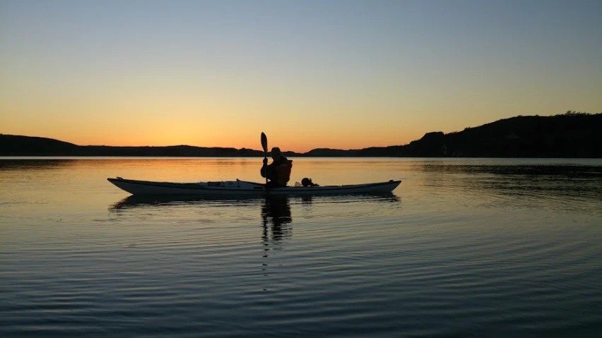 a man in a small boat at sunset