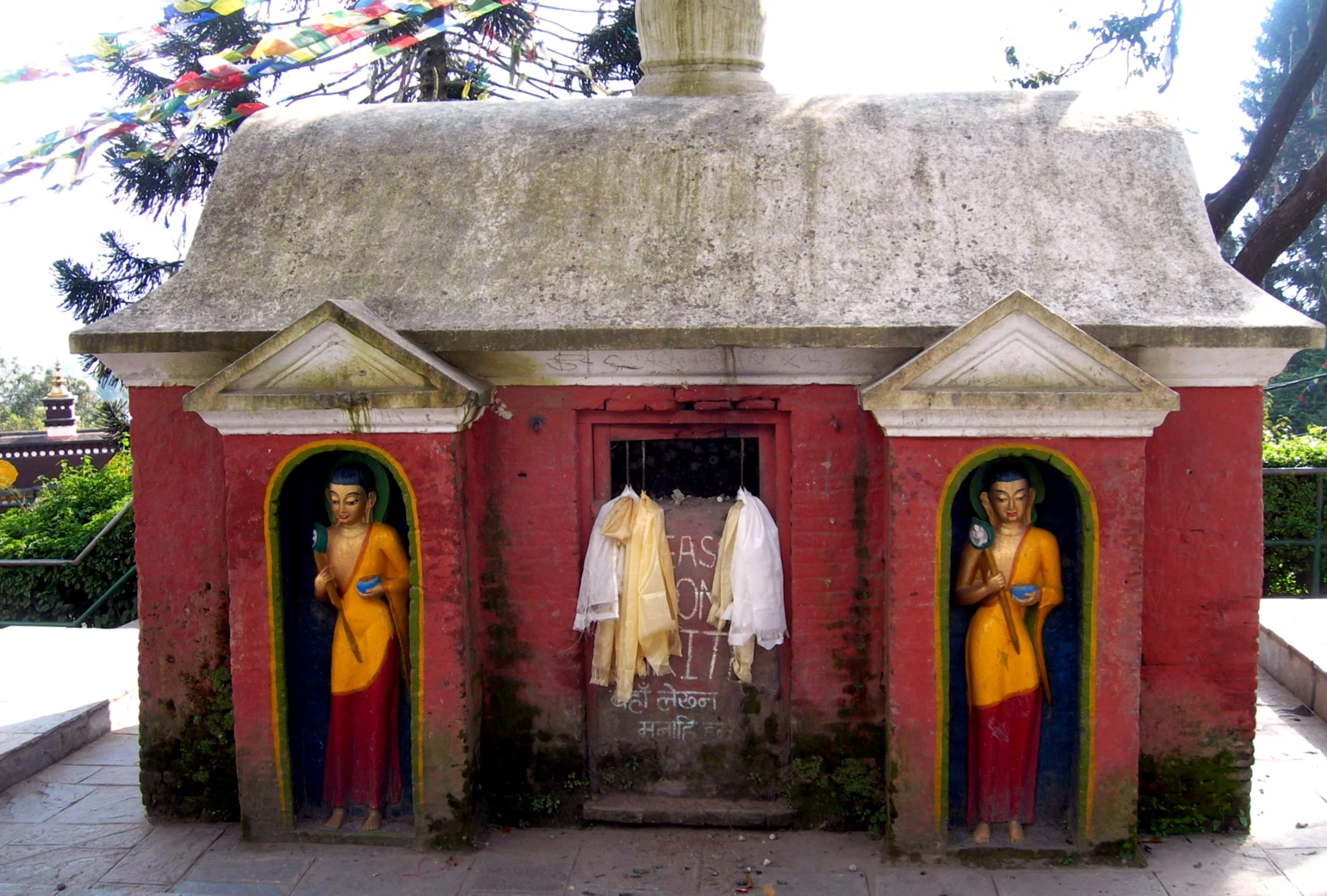 a couple of statues sit in doorways by some trees