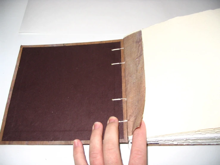 an open book and hand are shown on the table