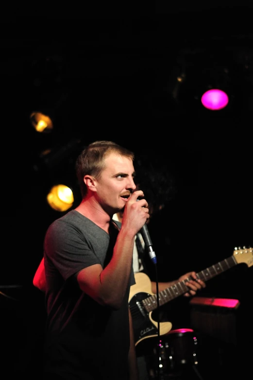 a man holding a microphone and playing a guitar