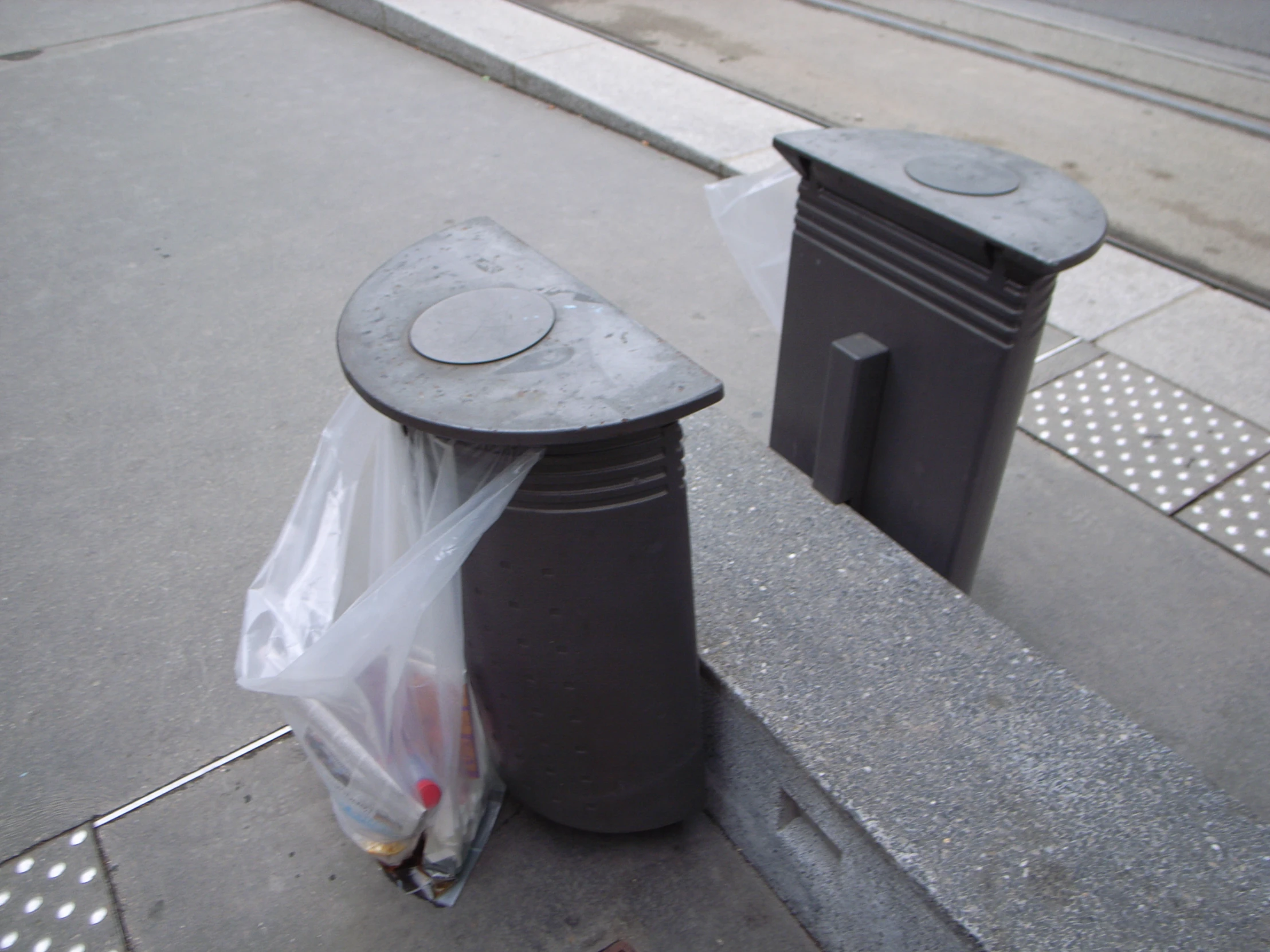 trash cans sitting on a sidewalk next to a street