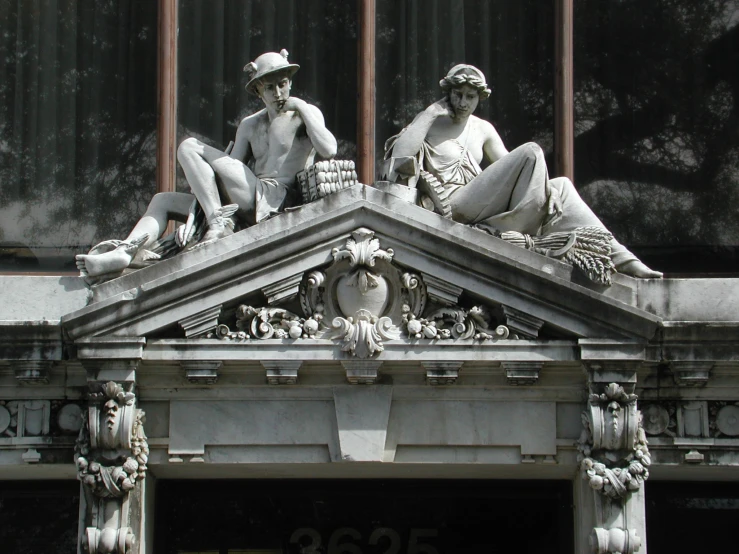 a couple of statues sitting on top of a tall building