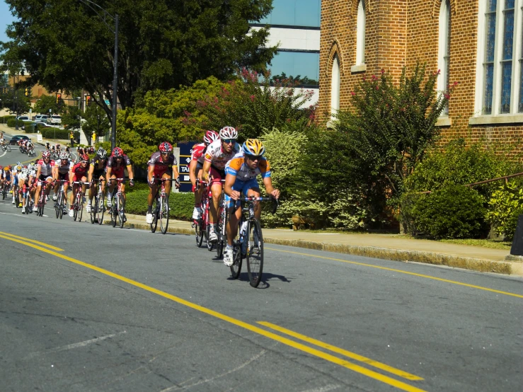 a line of cyclists with helmets riding down a road