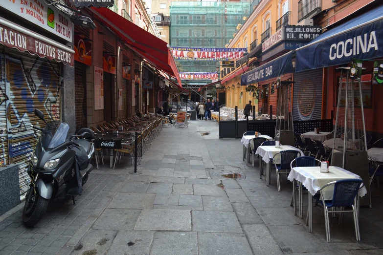 a street with lots of chairs and tables next to shops