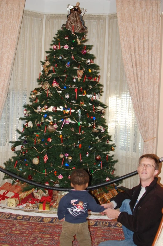 a man and boy are looking at the christmas tree