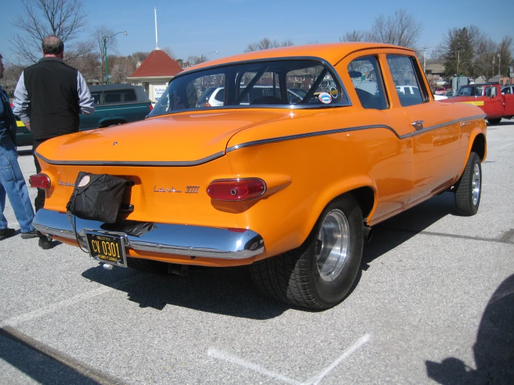 a large orange classic vehicle on display in the parking lot