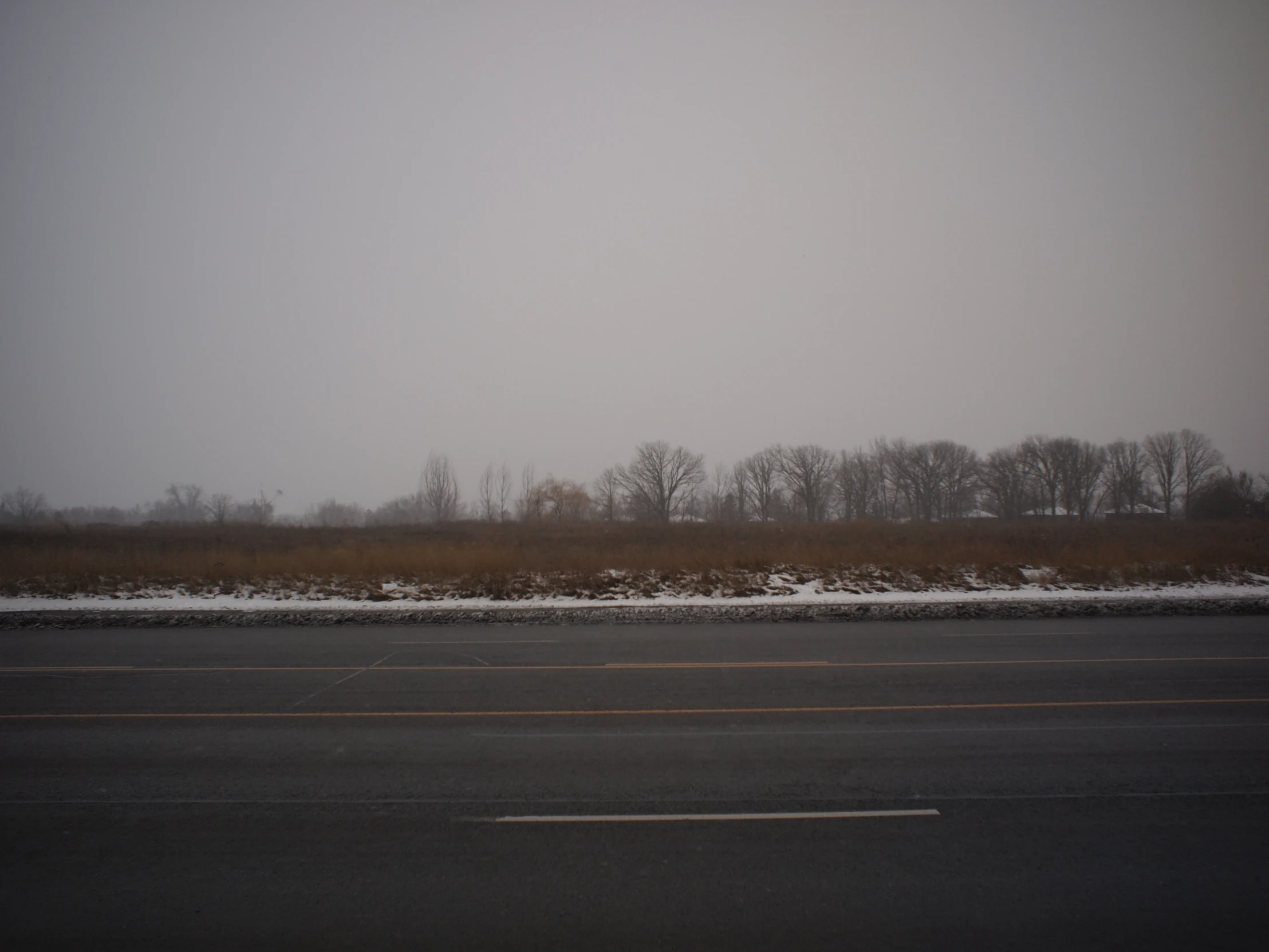 an empty road with a large field on the side of it