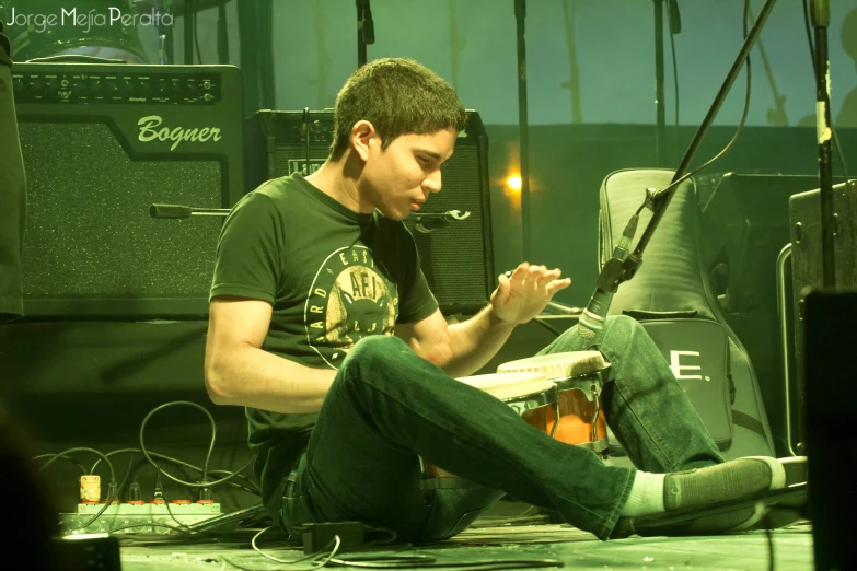 a young man sitting on the floor with his hands in his pockets