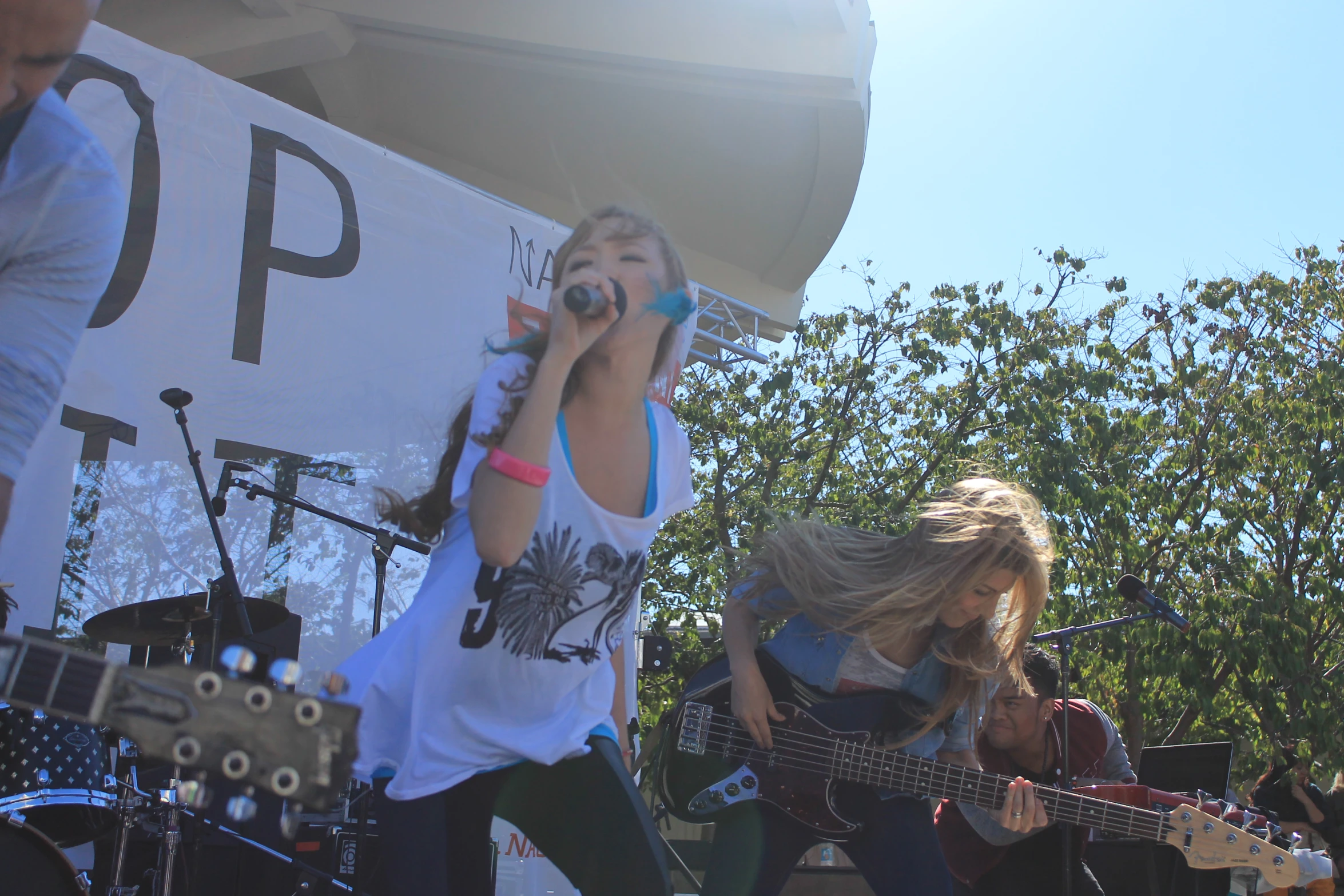 two s singing and playing guitars in front of an outdoor band