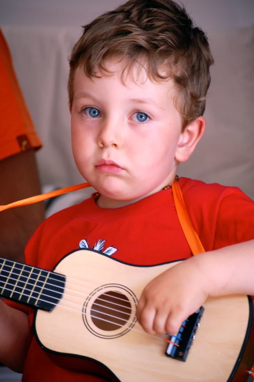 there is a boy with a small guitar on the lap