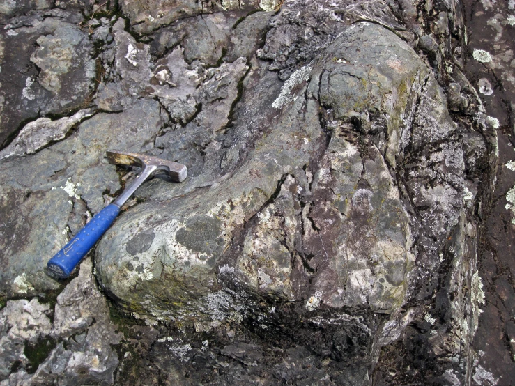 an old and rusty hammer is lying on the rocks