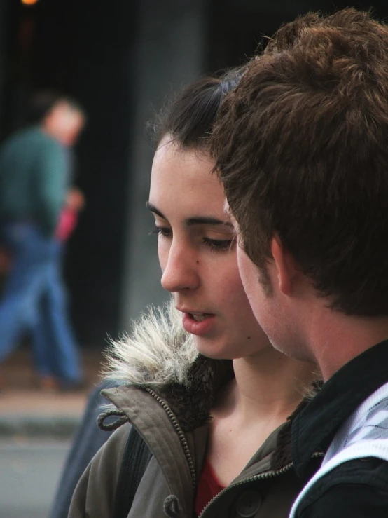 a man and woman on a sidewalk with one of them looking down at soing