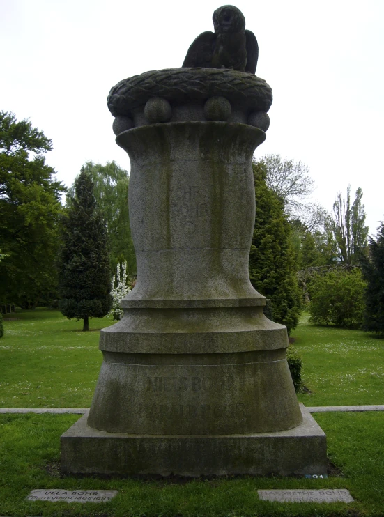 a large statue sits in the grass near trees