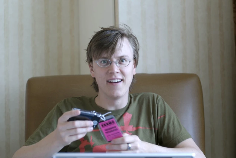 a man wearing glasses holding up a cell phone