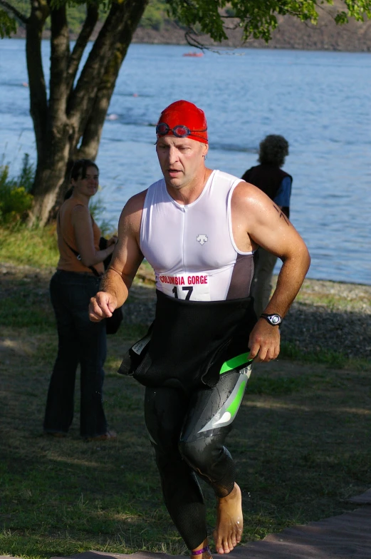 a man in a running suit runs near the water