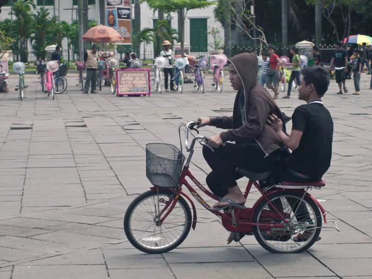 two people riding a bike on a sidewalk