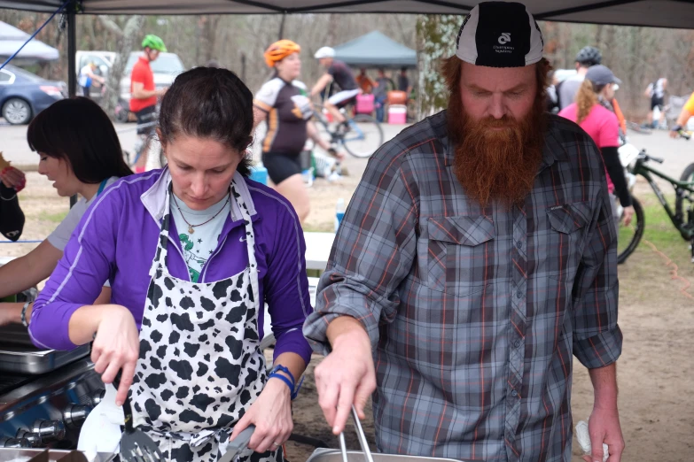 a man and woman prepare food under an awning