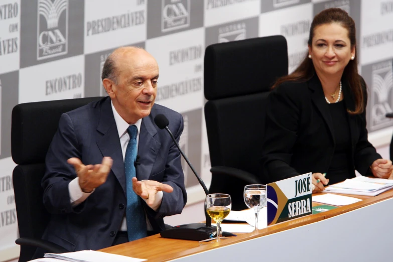 two people sitting in chairs at a press conference