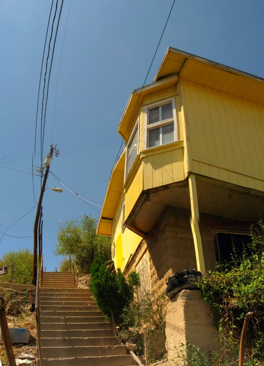 yellow house with red door and steps leading up to it