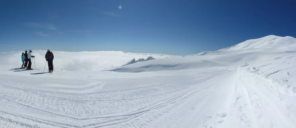 three snow skiers stand on top of a mountain