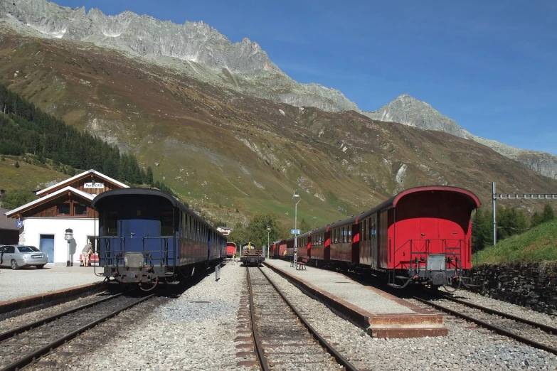 three train cars on one track with mountain backdrop