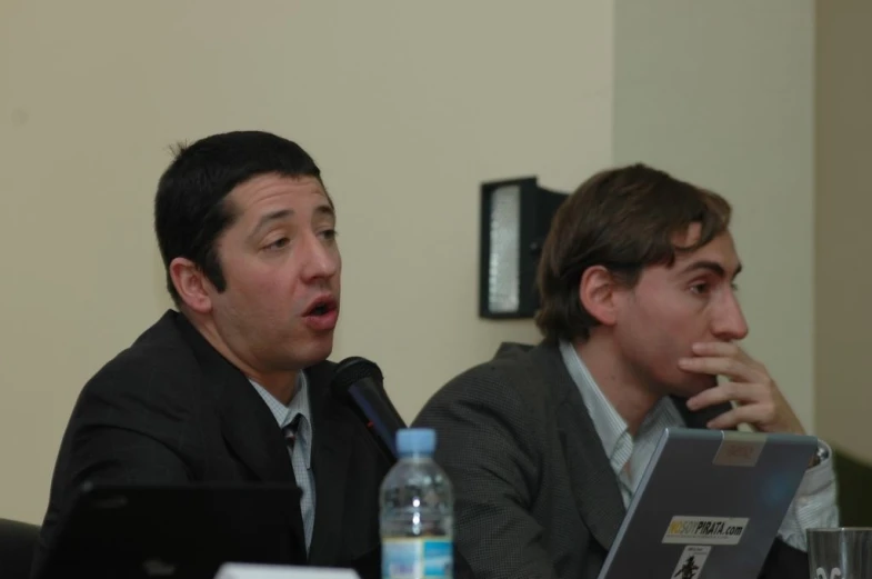 a couple of men at a table with a laptop