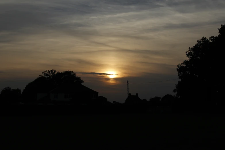 the sun in the sky over some trees