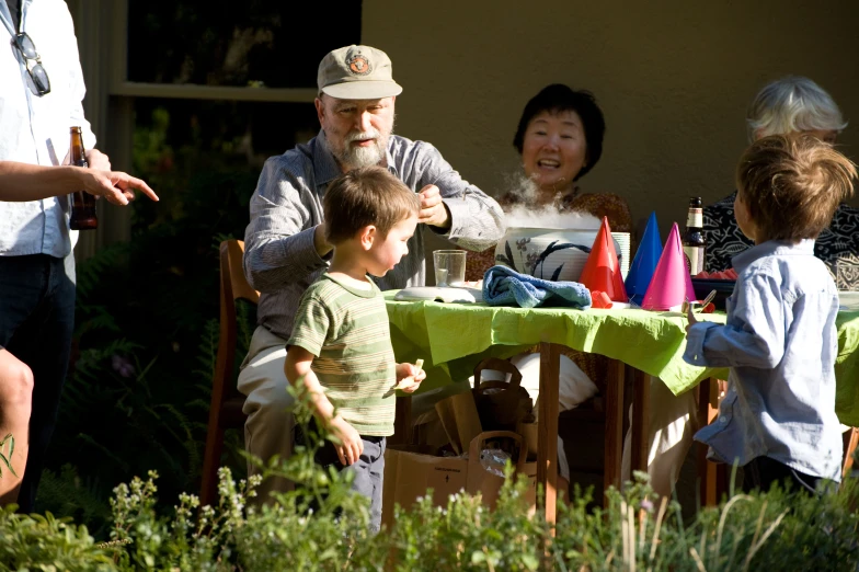 an elderly gentleman sitting at a table surrounded by young children