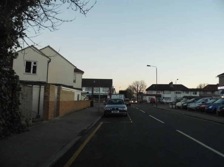 a city street with several parked cars in front of houses