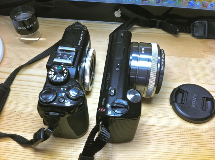 two cameras sitting on top of a table next to a laptop