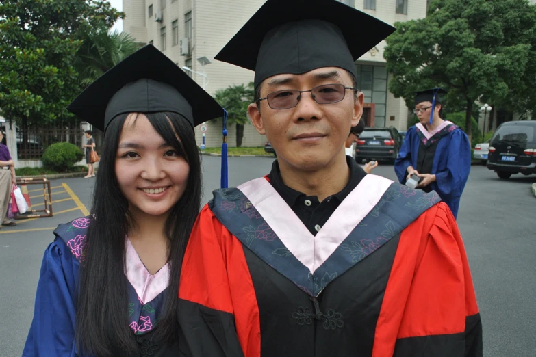 two people standing next to each other in graduation robes