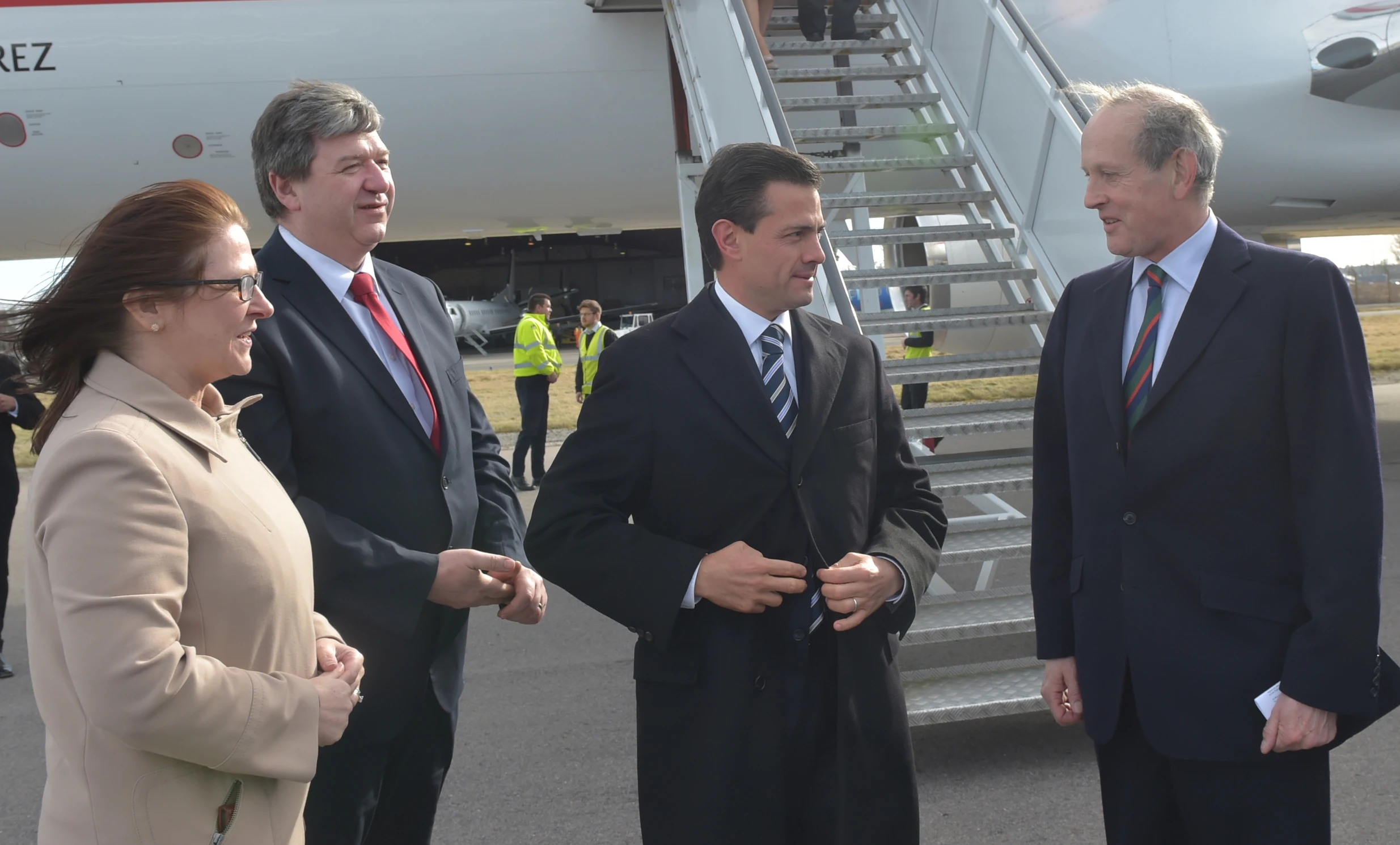 three men standing outside a big plane talking to each other