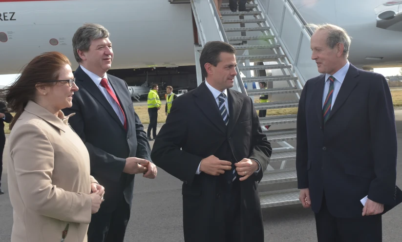 three men standing outside a big plane talking to each other