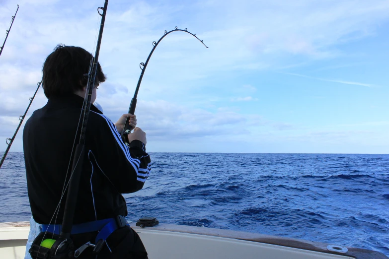 man in the back of boat holding a large fishing rod