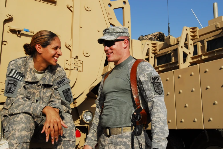 a couple of men and women standing next to an army tank