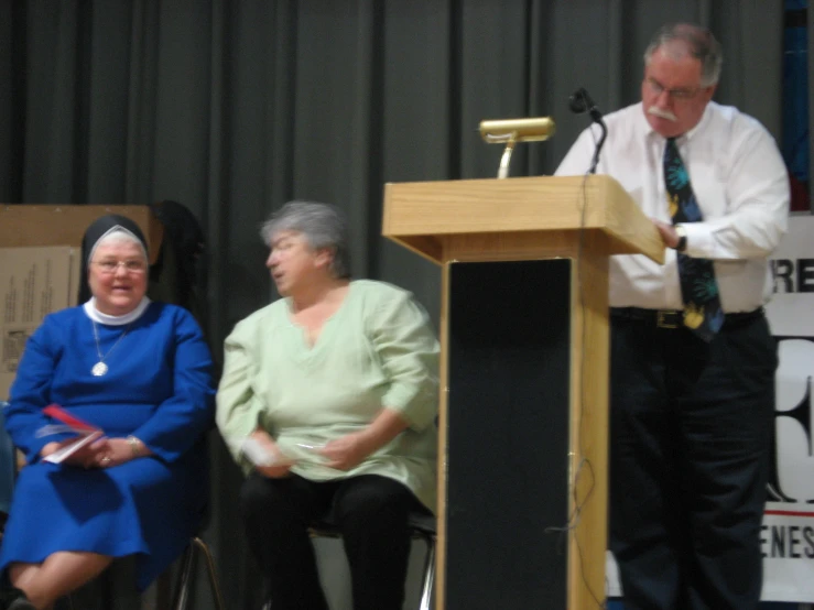 an old lady and an older man are in the chair at a podium